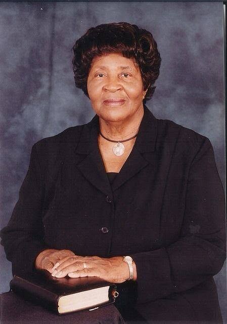 Portrait of Elder Berline Graham, seated, wearing a dark suit, her hands resting on a Bible.